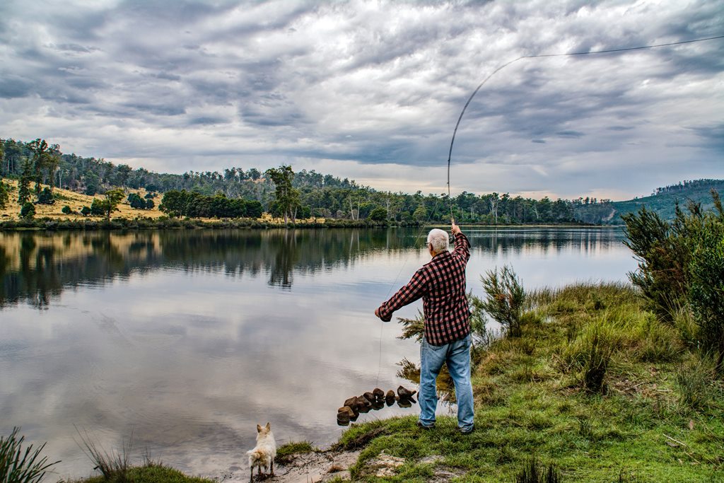 Old man fishing with his dog